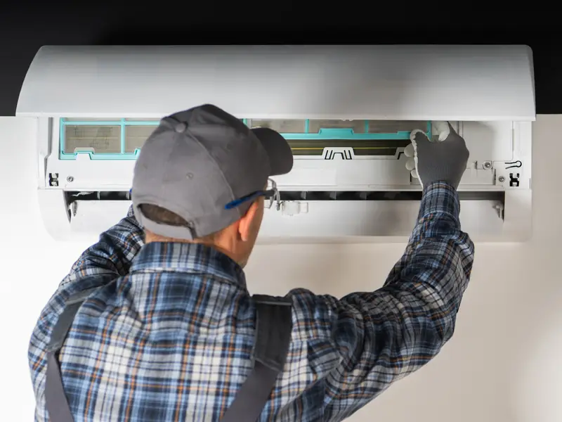 Technicien contrôlant une unité intérieure de climatisation