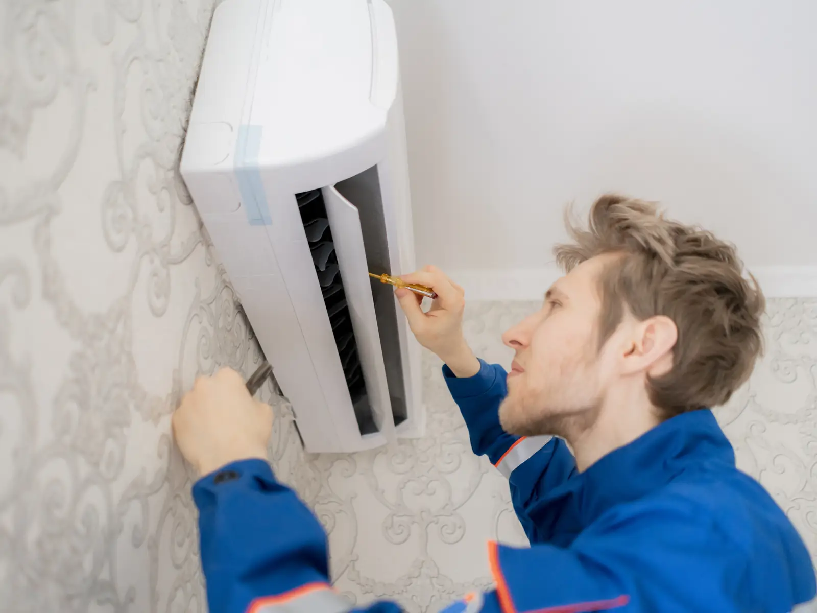 Technicien inspectant un climatiseur mural dans une maison de Mouans-Sartoux