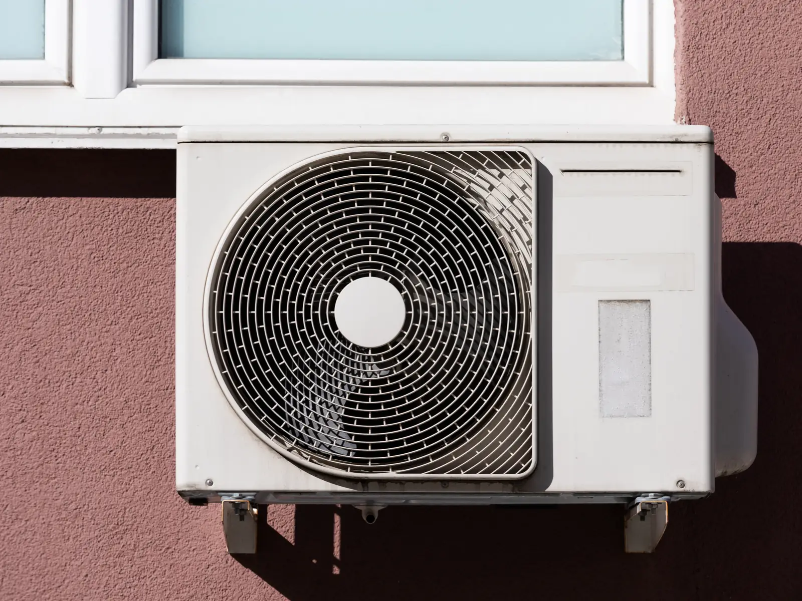 Groupe extérieur de climatisation fixé sous une fenêtre à Saint-Laurent-du-Var